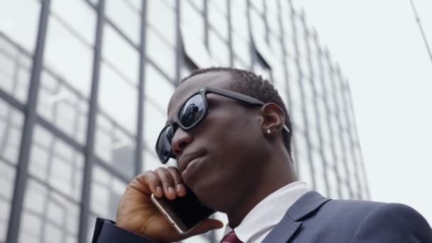 Viehättävä komea musta liikemies puhuu puhelimessa kadulla
 - Materiaali, video