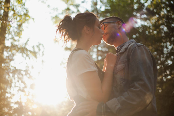 A beautiful young couple kiss in the forest - Фото, изображение