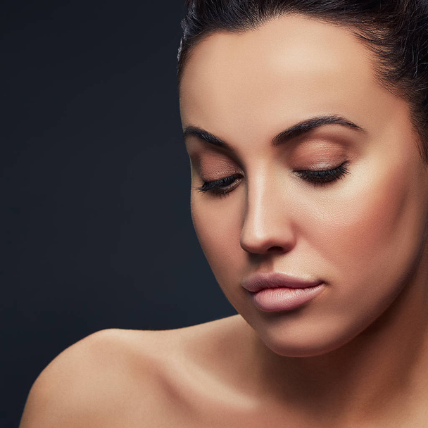 Portrait de femme brune avec maquillage naturel sur fond sombre
  - Photo, image