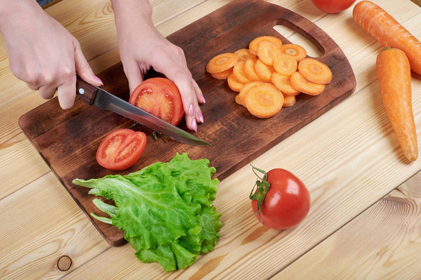 close up of female hand cutting tomato on cutting board at home, cooking, food and home concept - Foto, Imagem