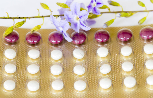 orale anticonceptiva vrouw voor die niet willen hebben baby eten geboortebeperking pillen met paarse bloemen  - Foto, afbeelding