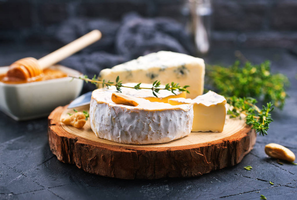 various types of cheese, blue cheese and brie with honey and nuts on wooden board  - Foto, Bild