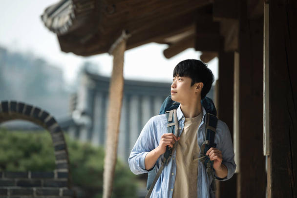 ein junger Mann macht eine Backpacker-Reise in einem traditionellen koreanischen Haus. - Foto, Bild