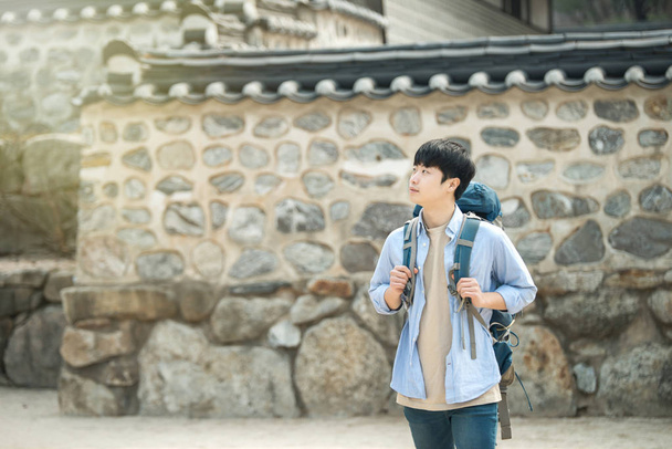 jovem fazendo uma viagem de mochila em uma casa tradicional coreana
. - Foto, Imagem