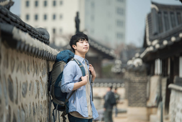 νεαρός άνδρας κάνει ένα backpacking ταξίδι σε μια κορεατική παραδοσιακή κατοικία. - Φωτογραφία, εικόνα