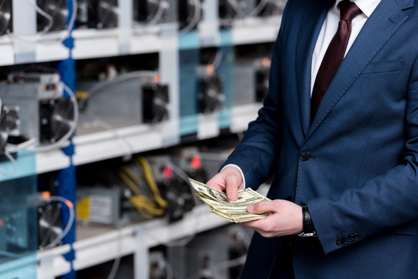 cropped view of businessman counting cash at ethereum mining farm - Photo, Image