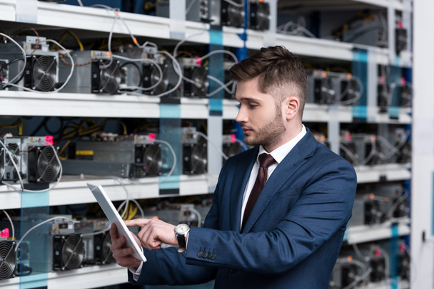 serious young businessman using tablet at ethereum mining farm - Photo, Image