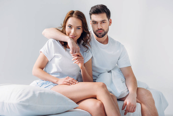 portrét člověka objímání přítelkyni zatímco sedí na posteli společně izolované Grey - Fotografie, Obrázek