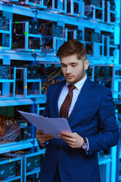 handsome young businessman reading documents at ethereum mining farm - Photo, Image