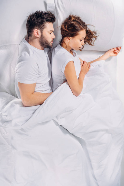 overhead view of young couple sleeping in bed together - 写真・画像