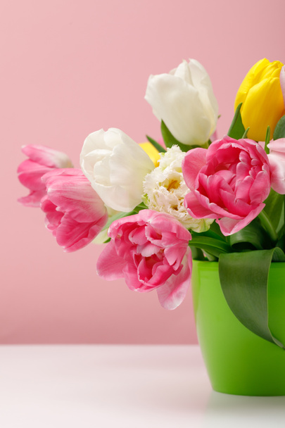 Tender blooming tulips in vase on pink background - Foto, afbeelding