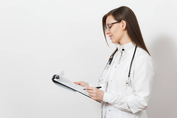 Αρκετά σίγουρος νεαρός γιατρός γυναίκα με στηθοσκόπιο, γυαλιά που απομονώνονται σε λευκό φόντο. Γυναίκα γιατρό σε ιατρική φόρεμα εκμετάλλευση κάρτα υγείας φάκελο Σημειωματάριο (Notepad). Νοσηλευτικού προσωπικού, ιατρική έννοια. - Φωτογραφία, εικόνα