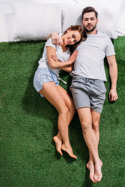 vue aérienne du jeune couple amoureux couché sur des oreillers sur de l'herbe verte
 - Photo, image