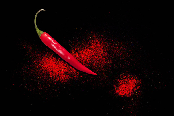 Hot chilli na černém pozadí. Suchá prášková pálivá paprika. - Fotografie, Obrázek
