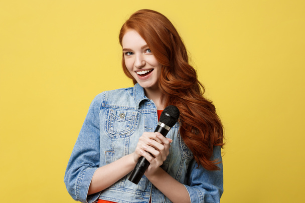 Lifestyle and People Concept: Expressive girl singing with a microphone, isolated bright yellow background. - Foto, Imagem