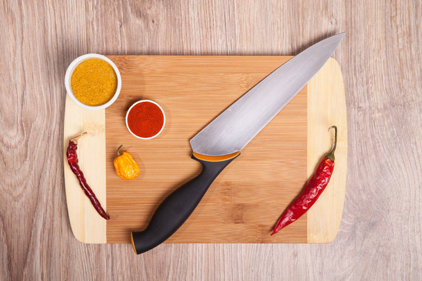 Red and yellow dry pepper on cutting board. Wooden kitchen board whit knife. Yellow dry habanero and sharp spice.  - Zdjęcie, obraz