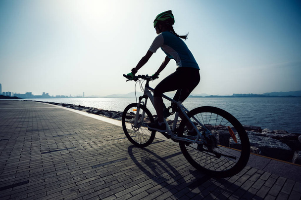 female cyclist riding mountain bike on seaside - Photo, Image