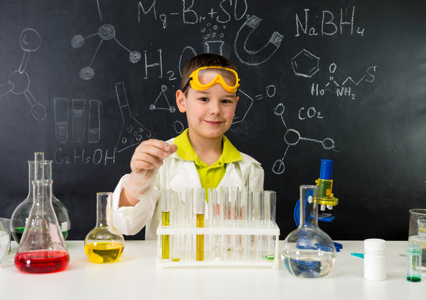 schoolboy gown and gloves watching chemical experiment in tube - 写真・画像