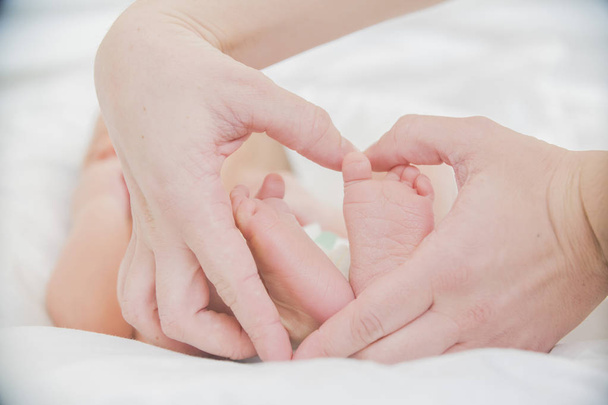 los pies del bebé en las manos de la madre de cerca
 - Foto, imagen