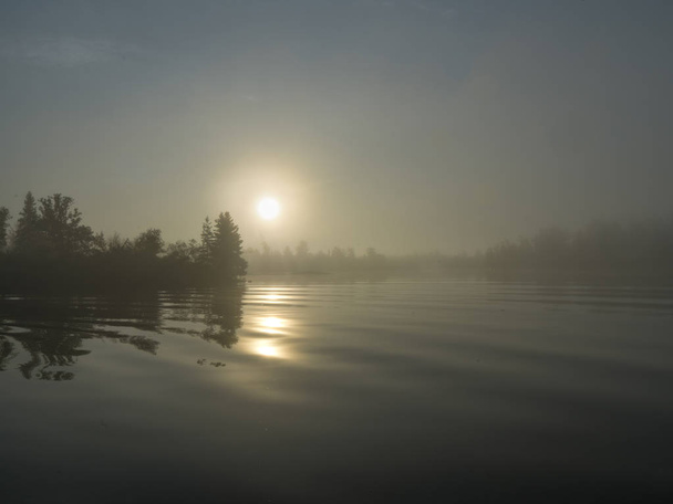 夕暮れ時、森の中の湖、オンタリオ州、カナダの湖の木の反射 - 写真・画像