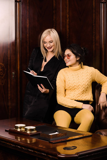 Two attractive young women sits in a beautiful office - Foto, afbeelding