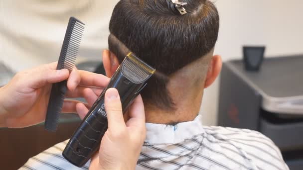 Close up de homens corte de cabelo com cortador de cabelo na barbearia. Homens Cabeleireiros. Barbeiro corta a máquina do cliente para cortes de cabelo
. - Filmagem, Vídeo