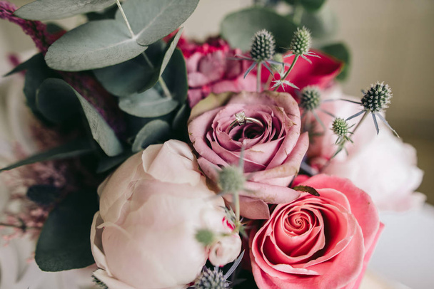 Anillo de compromiso dorado entre rosas en precioso ramo
 - Foto, Imagen