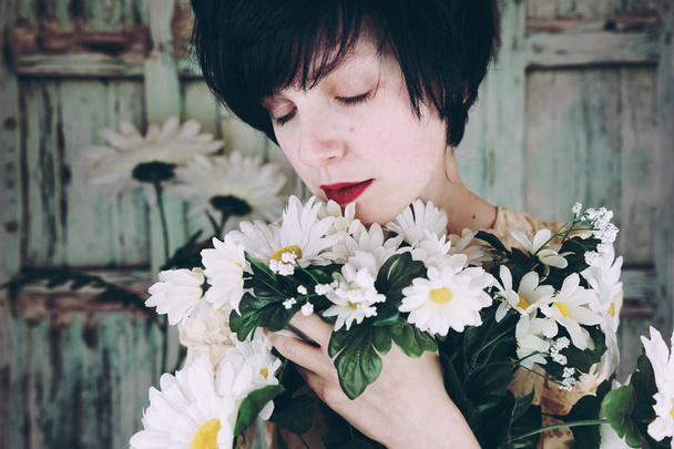 foto de close-up de jovem morena com lábios vermelhos segurando flores lindas margaridas brancas - Foto, Imagem