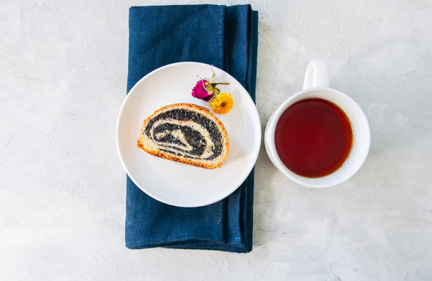 Haşhaşlı rulo dilim servis bir tabak ve bir fincan çay üzerinde bir - Fotoğraf, Görsel
