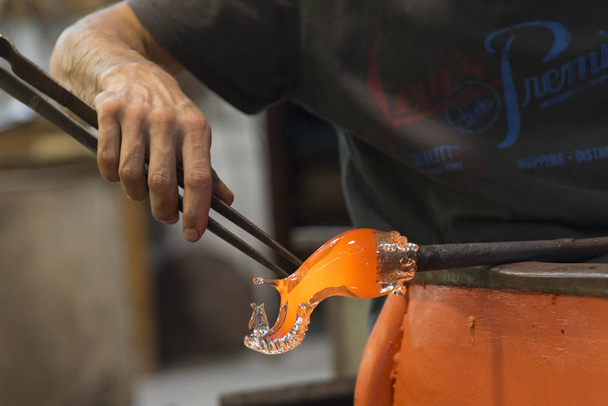 Mann arbeitet mit geschmolzenem Glas mit Pinzette in Glasfabrik, Murano, Venedig, Venetien, Italien - Foto, Bild