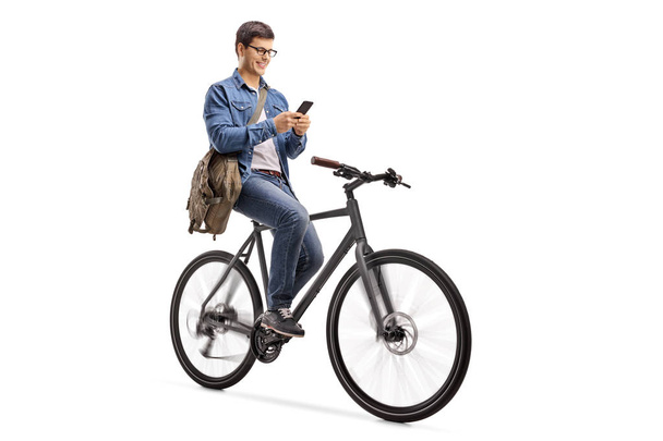 Young man riding a bicycle and using a phone isolated on white background - Zdjęcie, obraz