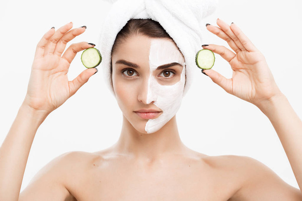 Beauty Youth Skin Care Concept - Portrait Beautiful Caucasian Woman apply cream and holding fresh cucumber in front of her face.Isolated over white background. - Foto, imagen