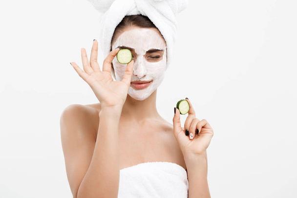 Beauty Youth Skin Care Concept - Retrato Mulher branca bonita aplicar creme e segurando pepino fresco na frente de seu rosto.. - Foto, Imagem