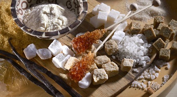 různé druhy cukru, vanilkové stick, bílý cukr, hnědý cukr blok, kusový cukr, handmaded, pokládání na dřevěné desce. v různých tvarech - Fotografie, Obrázek