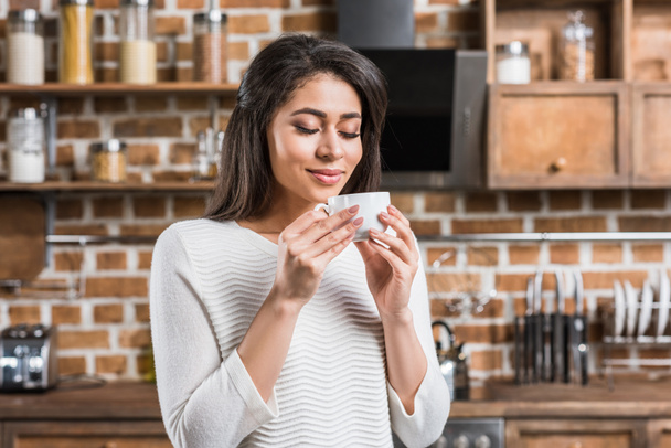 happy attractive african american woman enjoying cup of coffee in kitchen  - Foto, Imagem