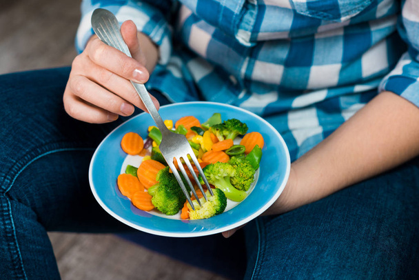 Girl with a plate of vegetables in hands - Foto, imagen