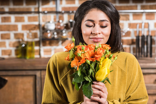 beautiful happy young woman with closed eyes holding bouquet of flowers at home - Zdjęcie, obraz