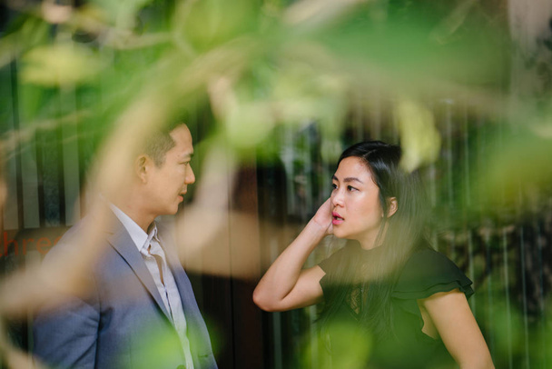 portrait of two professional business people walking and talking. They are deep in conversation as they walk on a street in a city in Asia. The man and woman are both professionally dressed. - Φωτογραφία, εικόνα