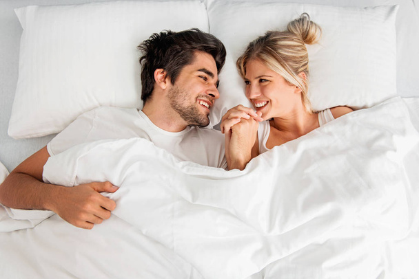 Young loving couple lying on the bed, enjoying - Foto, Imagem