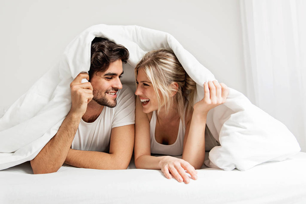 Young loving couple lying on the bed, enjoying - Foto, imagen