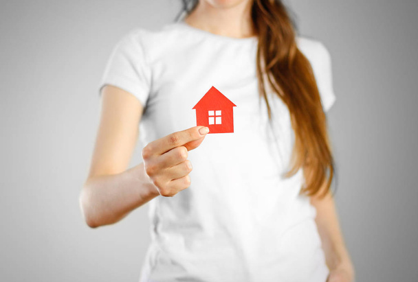 Ένα κορίτσι κρατά την εικόνα του σπιτιού. Μπρελόκ κόκκινο σπίτι - Φωτογραφία, εικόνα