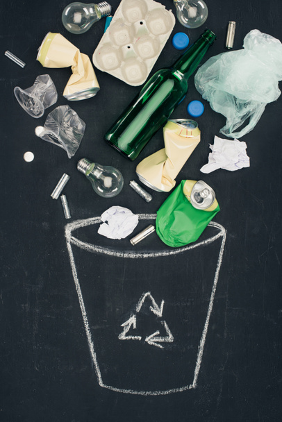various types of trash falling into drawn trash can with recycle sign on chalkboard - Photo, Image