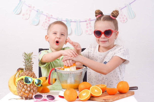 Healthy food for children: A girl and a boy are making orange juice - Fotoğraf, Görsel