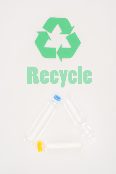 top view of plastic bottles with recycle sign on white - Foto, imagen