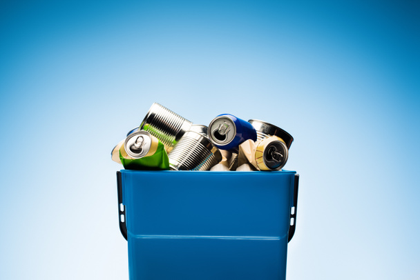 various metal cans in trash bin on blue - Foto, Imagen