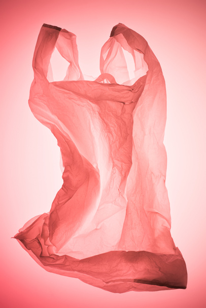 pastel pembe tonda ışık altında buruşuk şeffaf plastik torba - Fotoğraf, Görsel