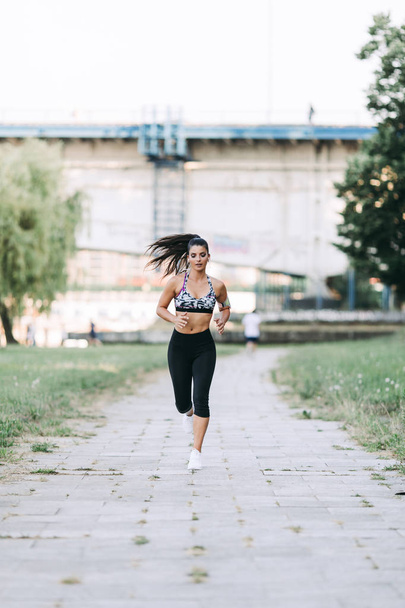 Beautiful athletic woman running outdoors - Foto, afbeelding