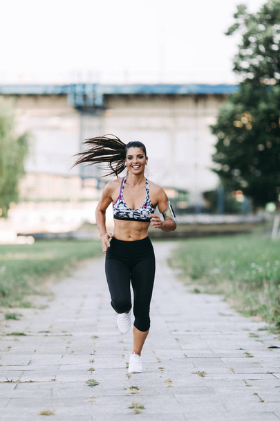 Beautiful athletic woman running outdoors - Photo, image