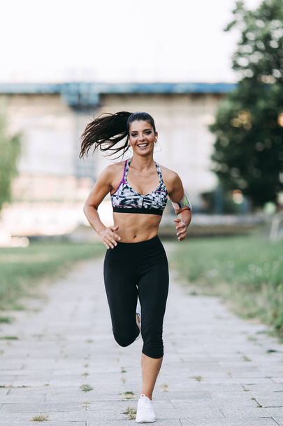 Beautiful athletic woman running outdoors - Photo, Image