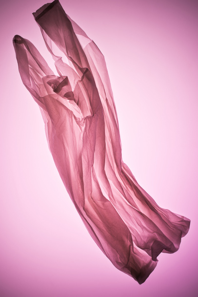 composition with crumpled transparent plastic bag under pink toned light - Photo, Image